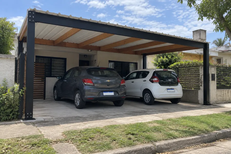 Cochera doble con viga de hierro negra, tirantes de madera y techo de isopanel blanco, con dos autos